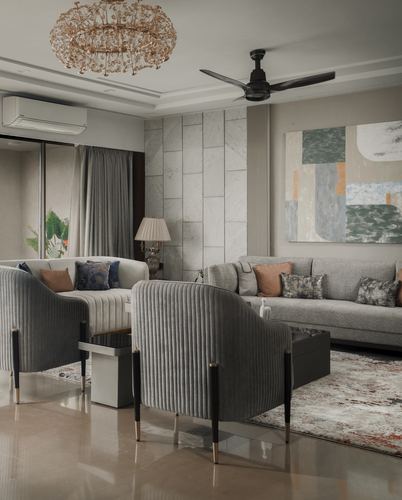 Grey living room with ribbed velvet armchairs, marble wall panel, and abstract art above sofa