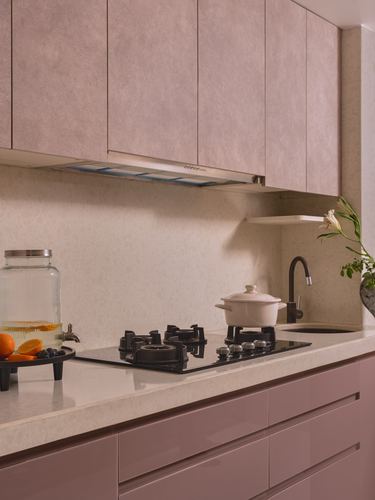 Blush pink kitchen counter with black gas hob, chimney hood, and textured wall panels