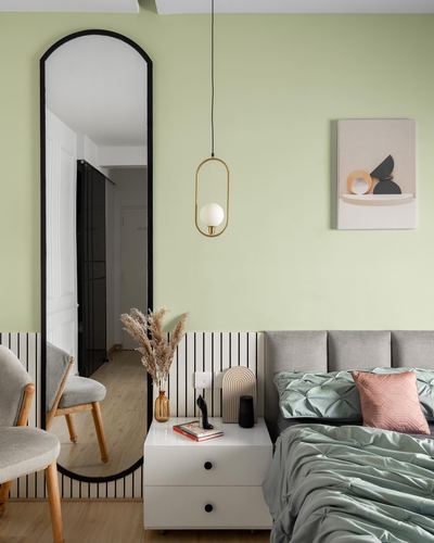 Sage green bedroom with arched mirror, brass pendant light, and pastel bedding