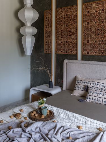 Bedroom with upholstered bed, patchwork tile wall panels, sculptural pendant lamp and walnut-filled tray