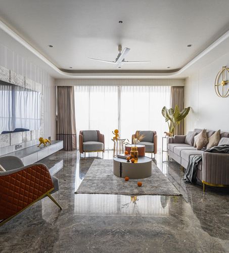 Symmetrical living room with marble floor, grey sofas, tan armchairs, and floor-to-ceiling sheer-curtained windows