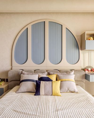 Bed with bouclé frame beneath a large arched blue-panelled headboard wall