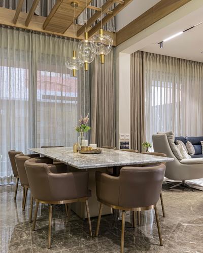 Dining room with marble table, brown leather chairs, brass legs, and layered glass pendant lights