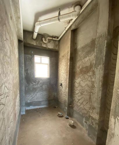 Unfinished bathroom with raw cement walls, exposed pipes, and scratched wall texture for plaster keying