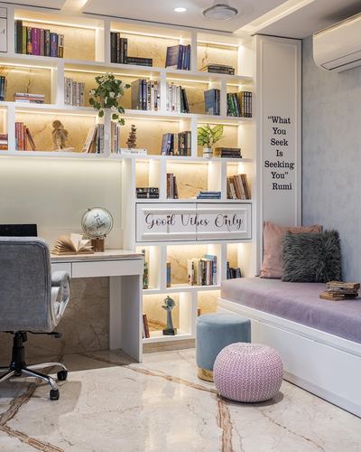 Home library with backlit stone shelving, study desk, and pastel velvet window seat