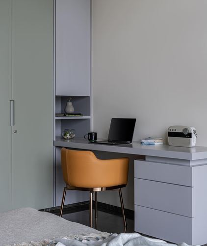 Grey built-in desk with mustard chair beside sage green wardrobe in bedroom study nook