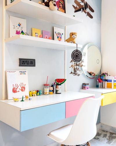 Kids study desk with pastel drawers, floating shelves of toys and art, round mirror above