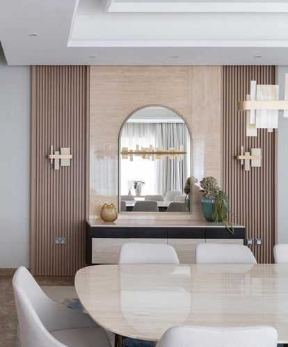 Dining room with fluted wood paneling, arched mirror, stone console, and oval marble-look table