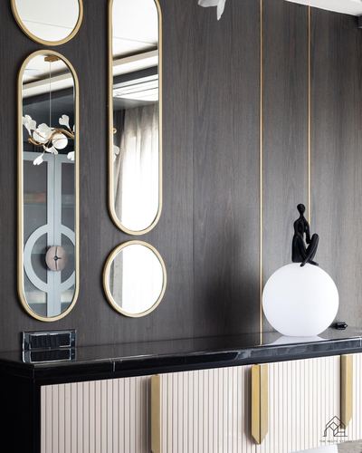 Wood-panelled wall with clustered mirrors above a black marble-topped console with fluted cabinetry