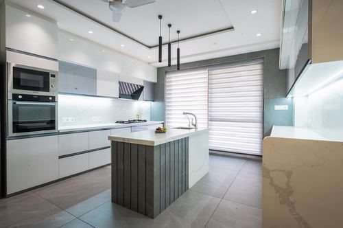 Modern white kitchen with fluted gray island, pendant lights, and marble-look countertops