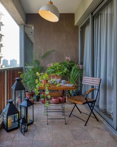 Balcony with wooden folding chairs, plants, lanterns, and a dome pendant light