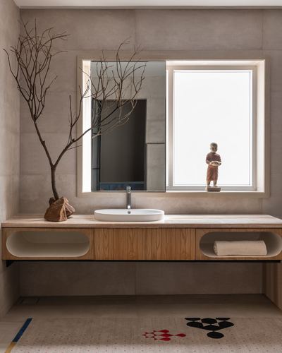 Wooden floating vanity with round sink under mirror beside window, dry branch on counter