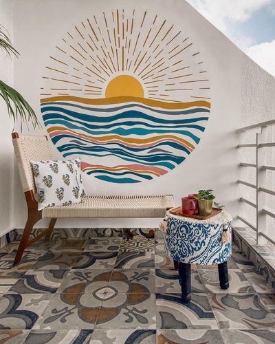 Balcony with cane bench, embroidered stool, patterned tiles and a circular sun mural on white wall
