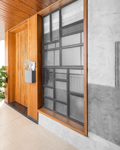 Entry foyer with fluted wood frame, black metal grid window, and textured grey plaster wall