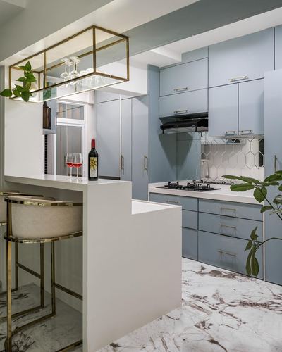 Blue lacquered kitchen with white marble counter, gold bar stools and hanging glass display cabinet