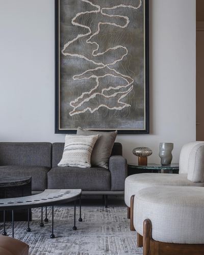 Grey sofa beneath large abstract artwork with side table, vases, and textured rug