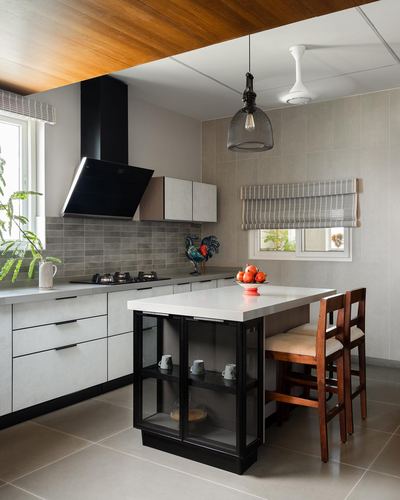 Modern kitchen with black island, wood ceiling accent, and black chimney hood