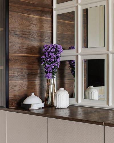 Sideboard vignette with flowers, ceramic vases, wood wall and grid mirror