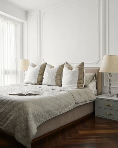 Neutral-toned bedroom with paneled walls, upholstered bed, and herringbone wood floor