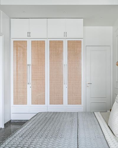 White wardrobe with cane-paneled doors beside a paneled door in a bedroom