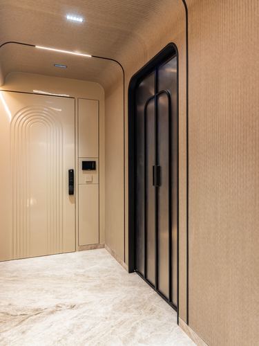 Curved foyer corridor with arched beige entry door and black-framed sliding glass door on stone flooring