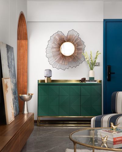 Green geometric sideboard with brass trim beneath a sunburst mirror in a styled foyer