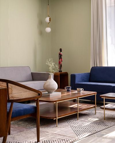 Living room with navy and grey sofas, cane armchair, wooden coffee table, and sage striped wall
