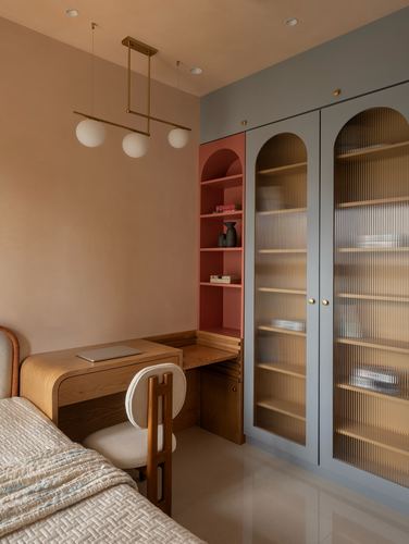 Study nook with arched terracotta bookshelf, reeded glass wardrobe, and wooden desk under globe pendant light