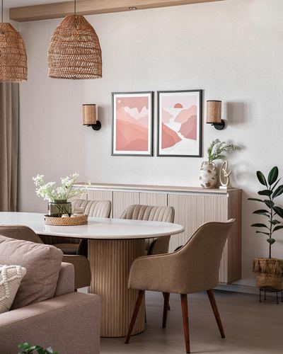 Dining area with round marble table, fluted wood sideboard, rattan pendants, and pink mountain artwork