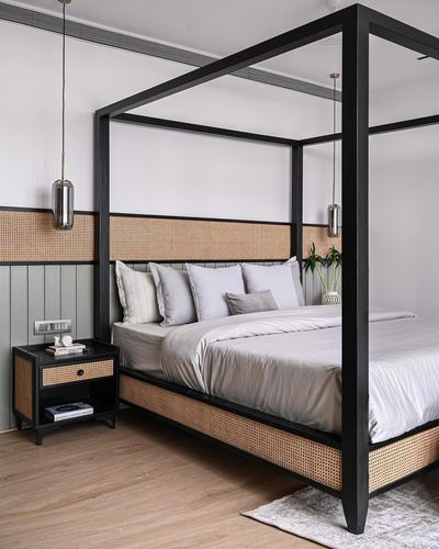 Bedroom with black four-poster bed, cane headboard, wainscoted sage wall, wood floor