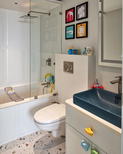 Kids bathroom with terrazzo floor, glass shower, teal sink and framed animal prints