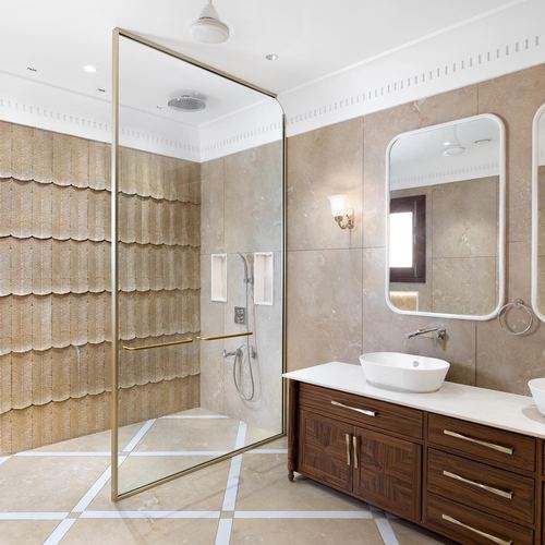 Bathroom with scalloped stone accent wall, glass shower, and dark wood vanity with double vessel sinks
