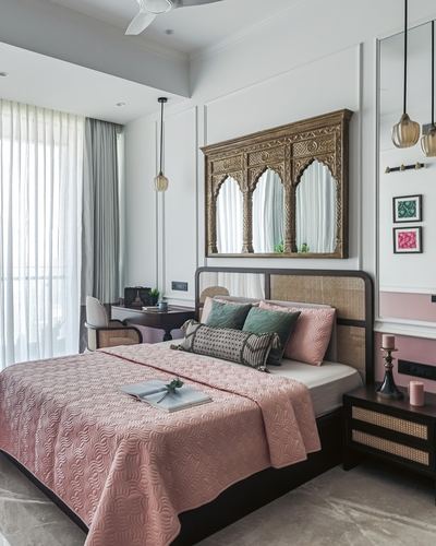 Bedroom with pink quilted bedspread, cane headboard, and carved arched mirror above bed