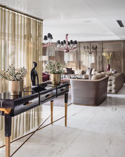 Opulent living room with gold chain curtain, black lacquered console, and tufted leather sofas on marble floor