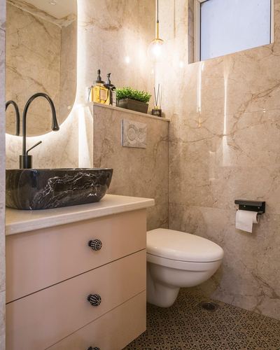 Marble bathroom with backlit mirror, dark stone vessel sink, wall-hung toilet and pendant light