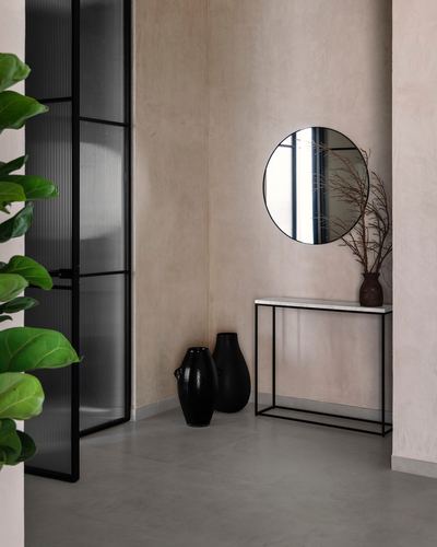 Minimalist foyer corner with round mirror, marble console table and black ceramic vases