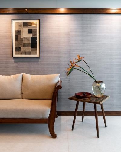 Beige wooden sofa beside a small side table with a glass vase of bird of paradise flowers