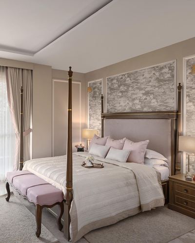 Elegant bedroom with dark wood four-poster bed, blush velvet headboard, and floral wallpaper accent panel