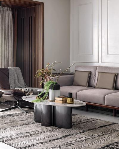 Living room with grey velvet sofa, marble coffee table, and leather recliner beside slatted wood partition