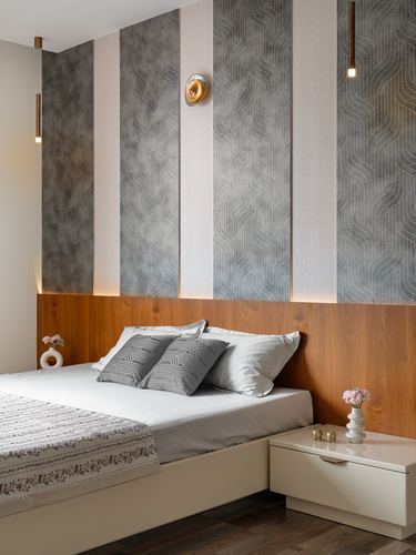 Bedroom with striped textured wallpaper above a warm wood headboard and cream bed