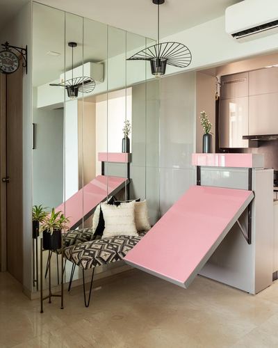 Mirrored foyer with pink fold-down table, patterned bench, and black pendant lights.