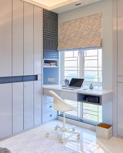 Built-in study desk with laptop below window, flanked by glossy wardrobes, in a Kolkata bedroom.