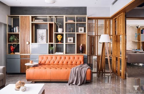 Living room with orange chesterfield sofa facing wooden display shelving and slatted partition