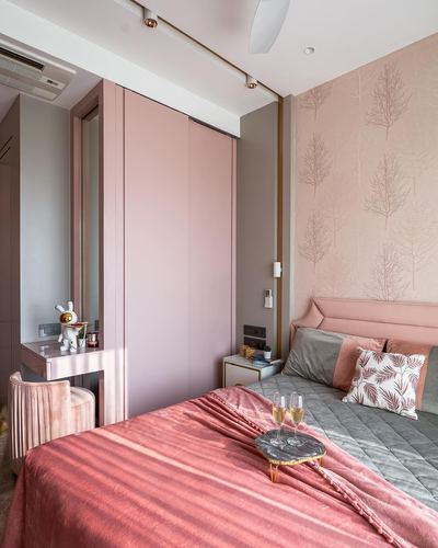 Pink art deco bedroom with tufted headboard, sliding wardrobe, patterned wallpaper and marble champagne tray on bed