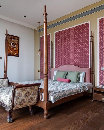 Bedroom with wooden four-poster bed, maroon patterned wall panels, and antique upholstered settee