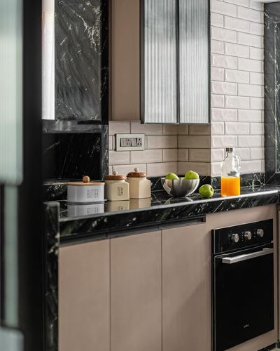 Kitchen corner with dark marble counter, fluted panel, tiled backsplash, and built-in oven
