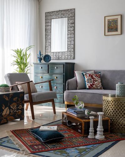 Living room with teal dresser, studded mirror, grey sofa, and patterned kilim rug