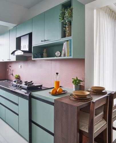 Sage green kitchen with pink textured backsplash and wooden breakfast counter with chairs