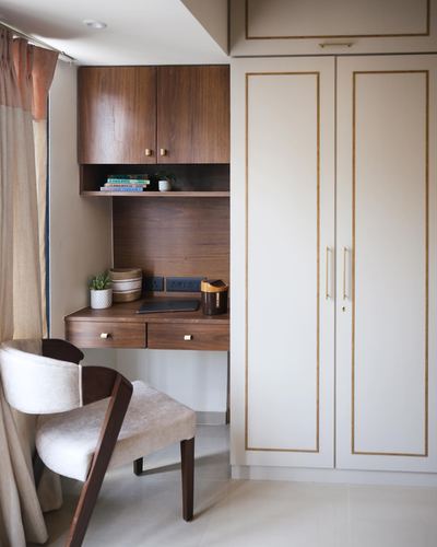 Corner study nook with wood desk, open shelf, wardrobe, and curved cream armchair.