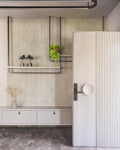 Entry foyer with fluted wood wall, floating console, black shelf, and large round door handle